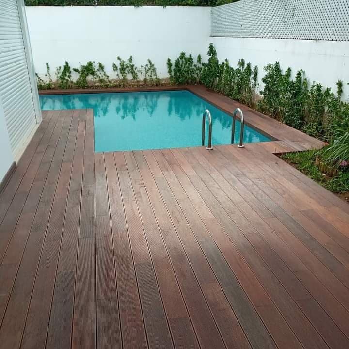 Vue du platelage brun et de l’accès à la piscine.